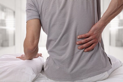 man with back pain using body pillow